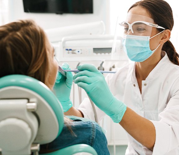 Dentist smiling while examining patient's teeth