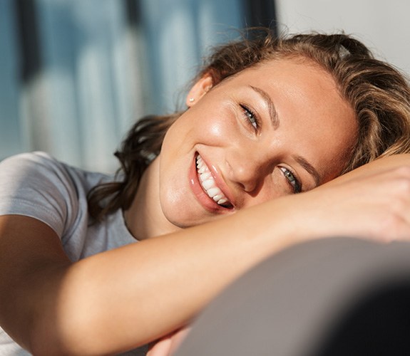 Smiling young woman leaning on sofa